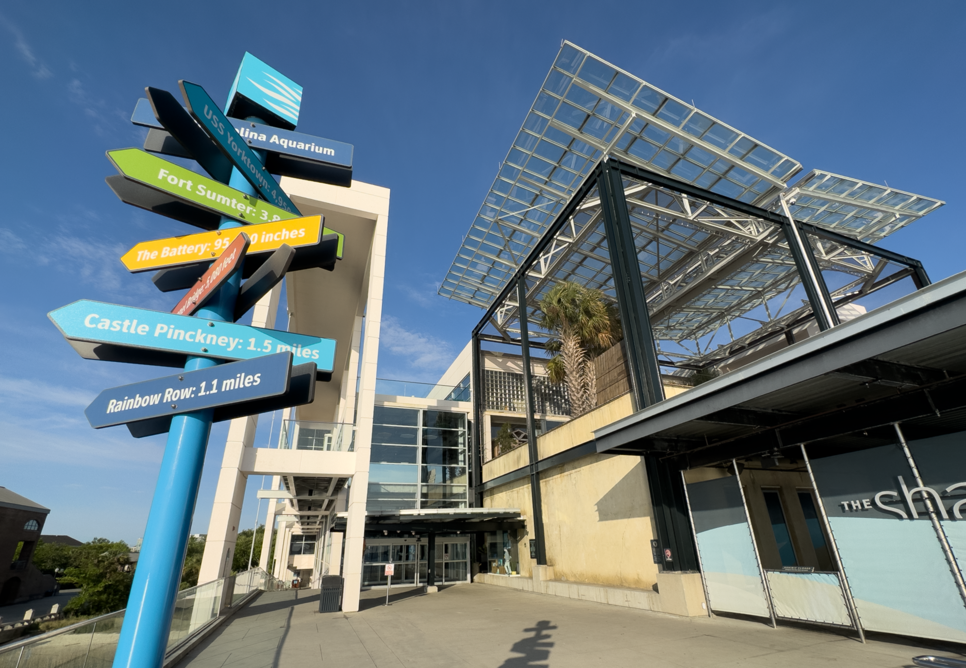 A wide-angle photo shows the guest entrance of the South Carolina Aquarium with a directional street sign in the foreground.