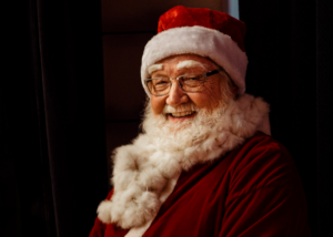 Santa Claus sits and smiles toward the camera